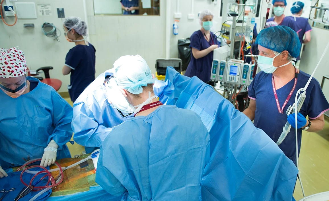 A surgical team performs a procedure in a high-intensity operating room, representing research into perioperative fluid management and its impact on patient recovery.