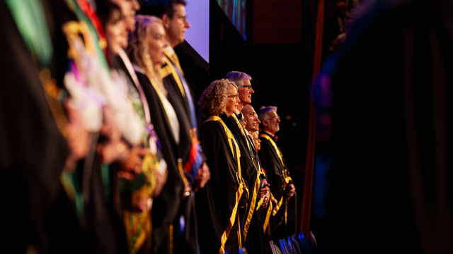 ANZCA and FPM fellows in their gowns on stage