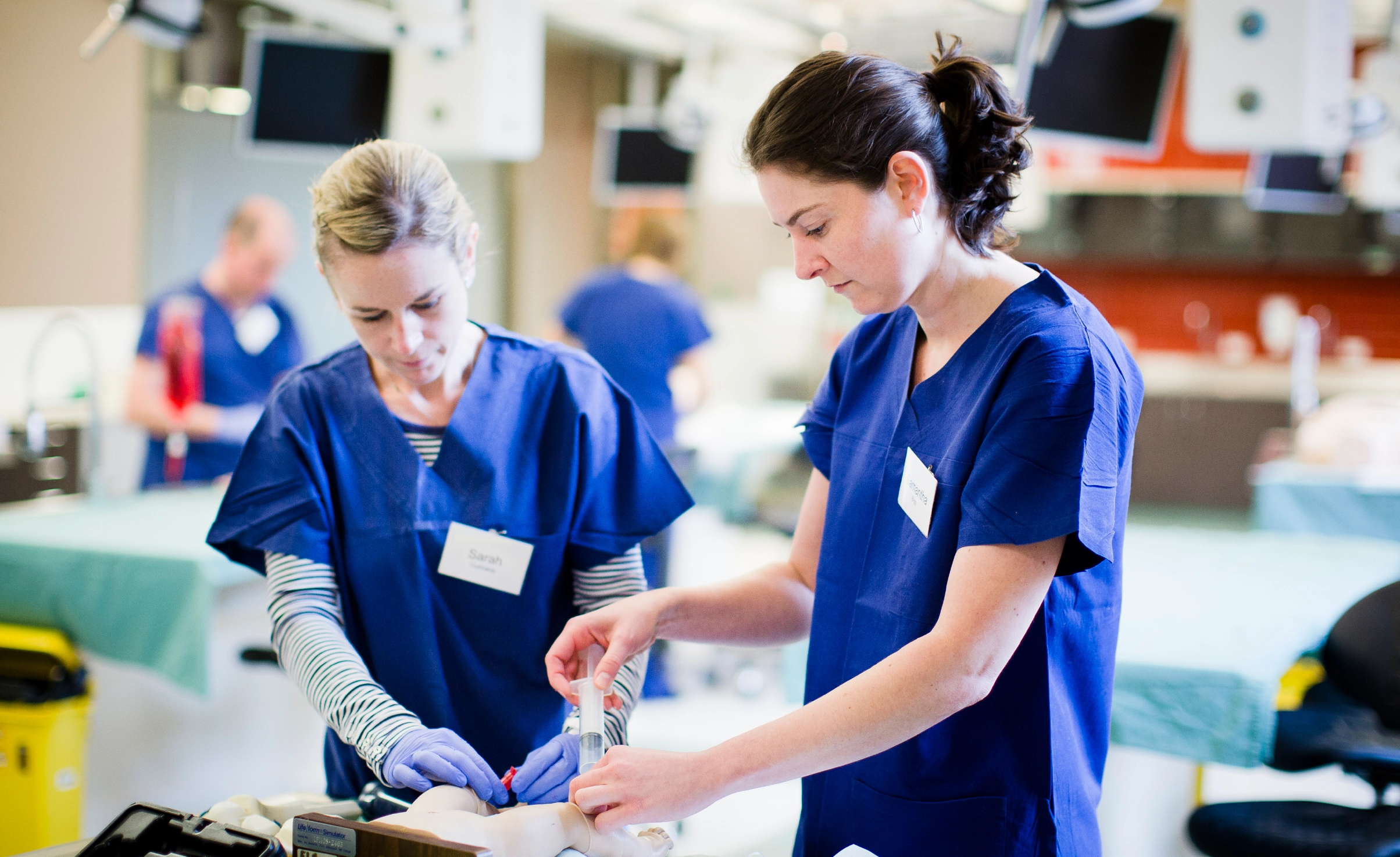 Two people in scrubs working on a simulation patient in hospital