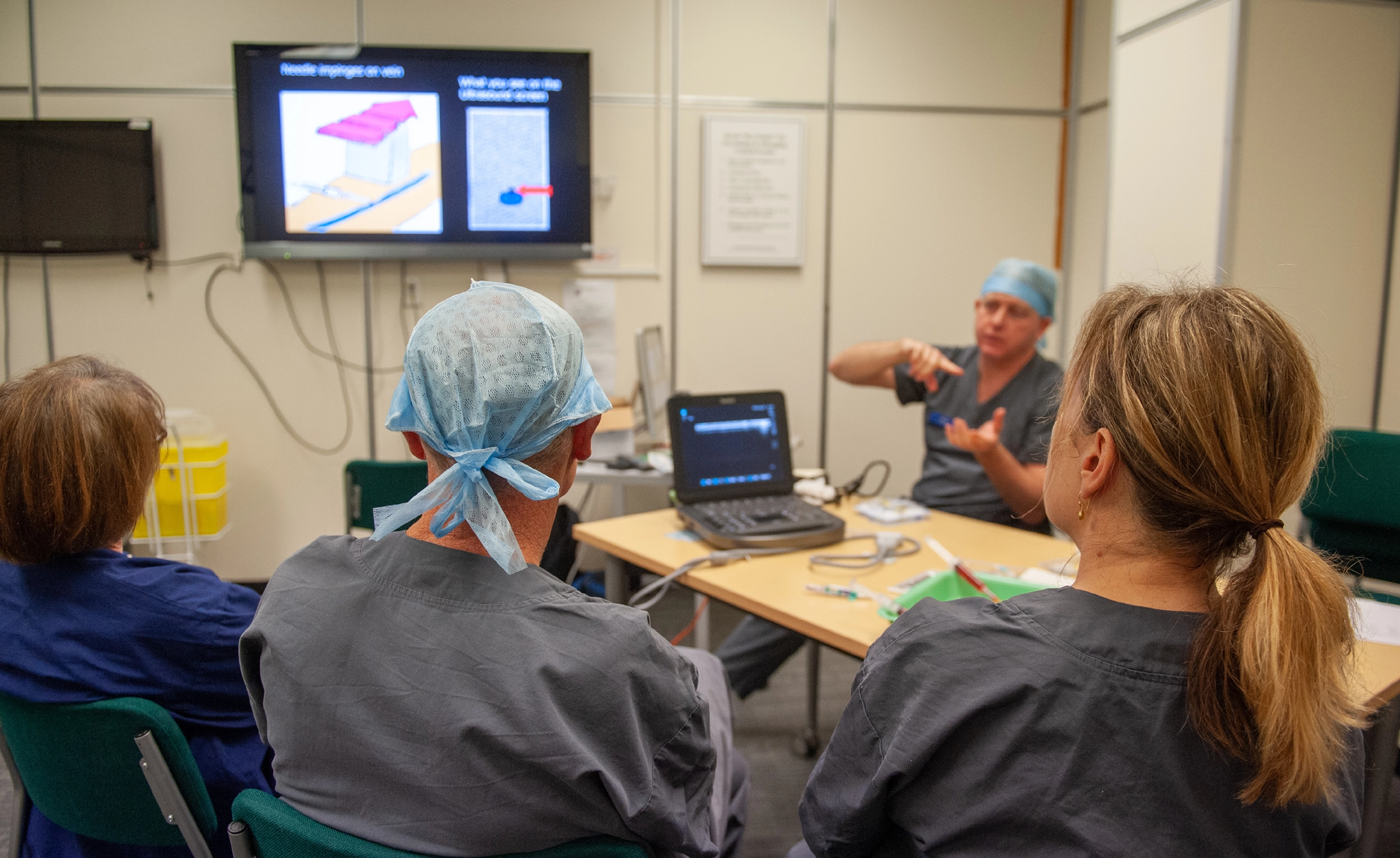 A group of doctor's looking at a screen while one doctor explains the diagram