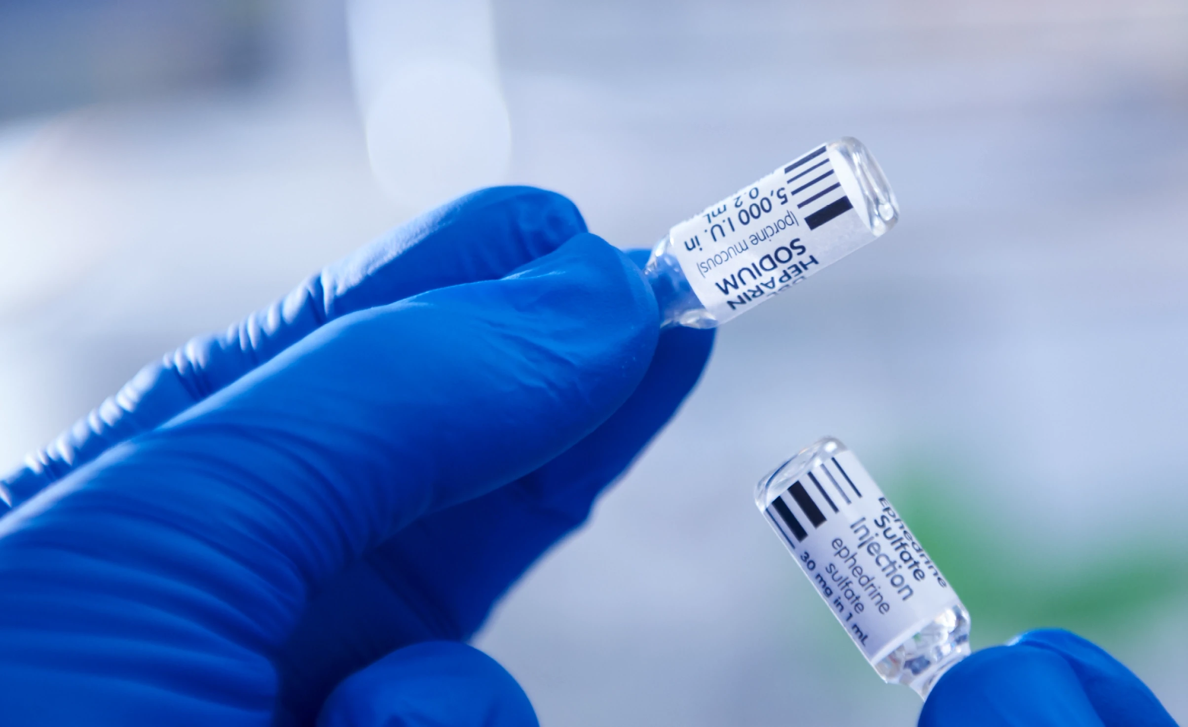 Photo of two hands holding vials of medicine