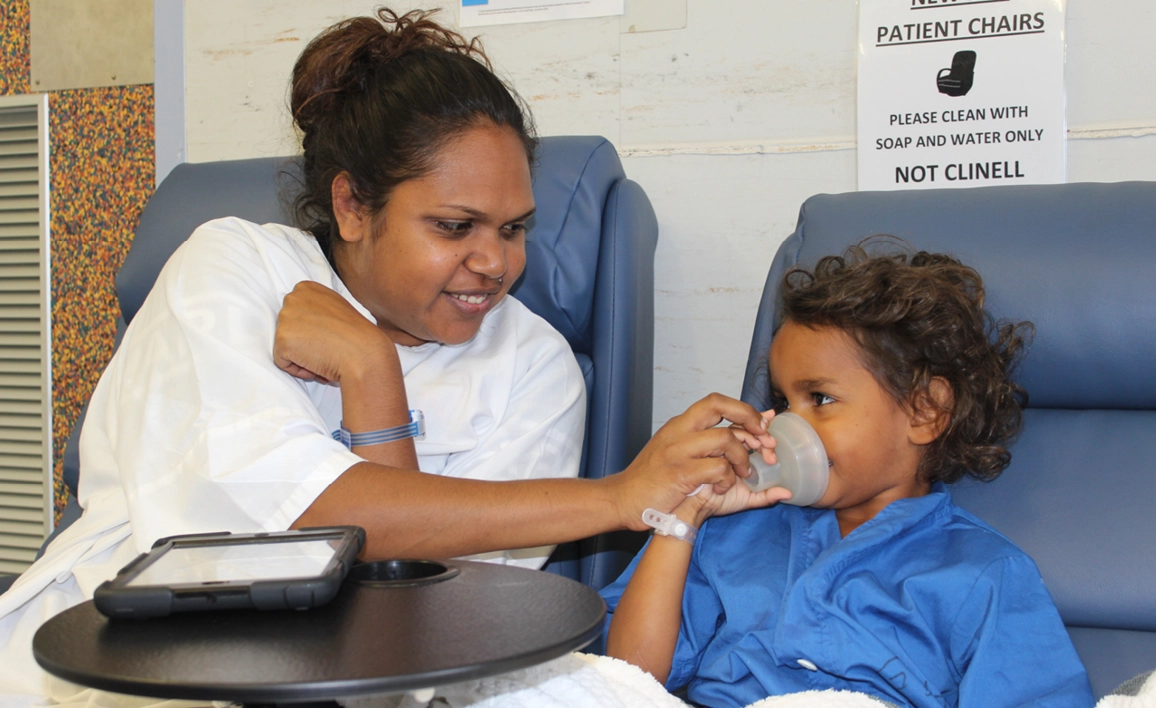 Aboriginal mother placing mask on her child's mouth and nose