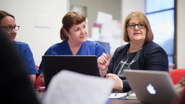 Female doctors talking around a computer