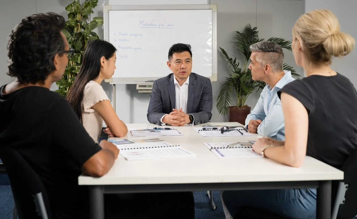 Group of people gather around a desk in a meeting