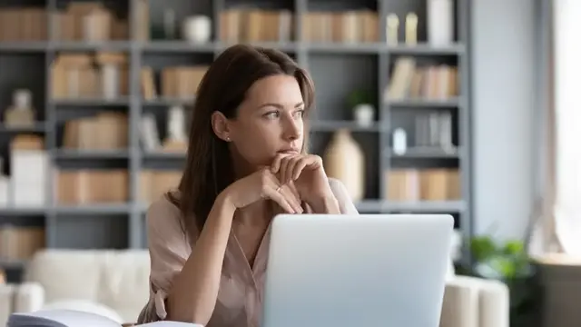 Woman sitting reflectively at computer