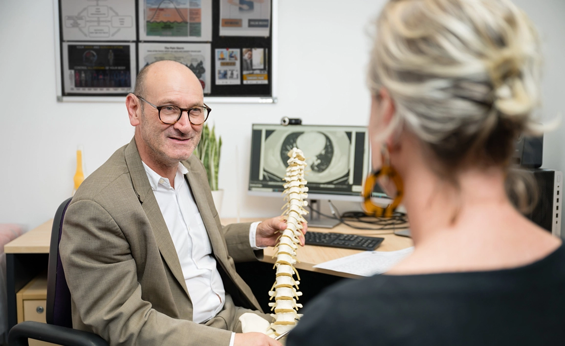 Doctor showing patient a model of a spine