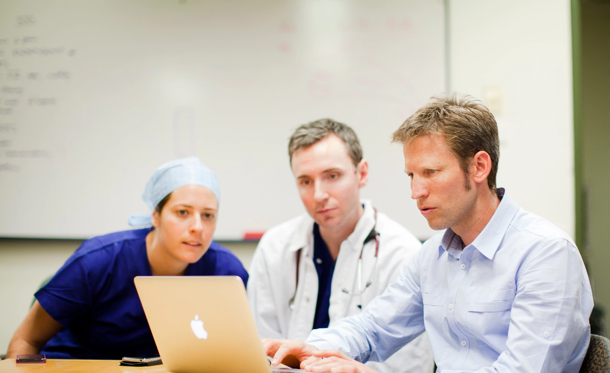 Three people looking at laptop screen