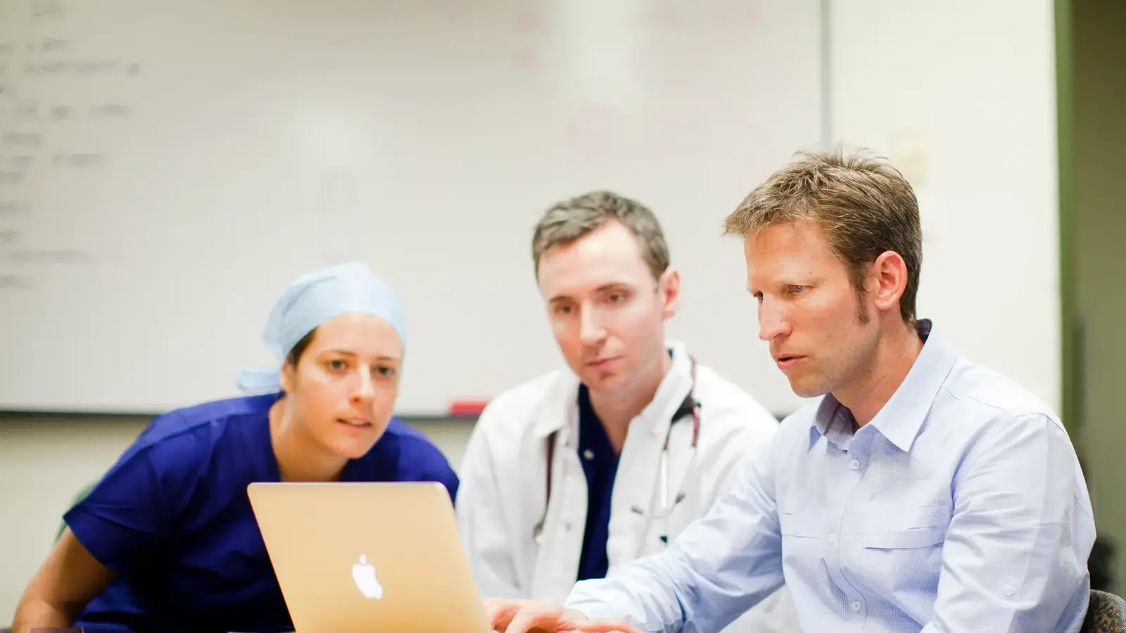 Three people looking at laptop screen