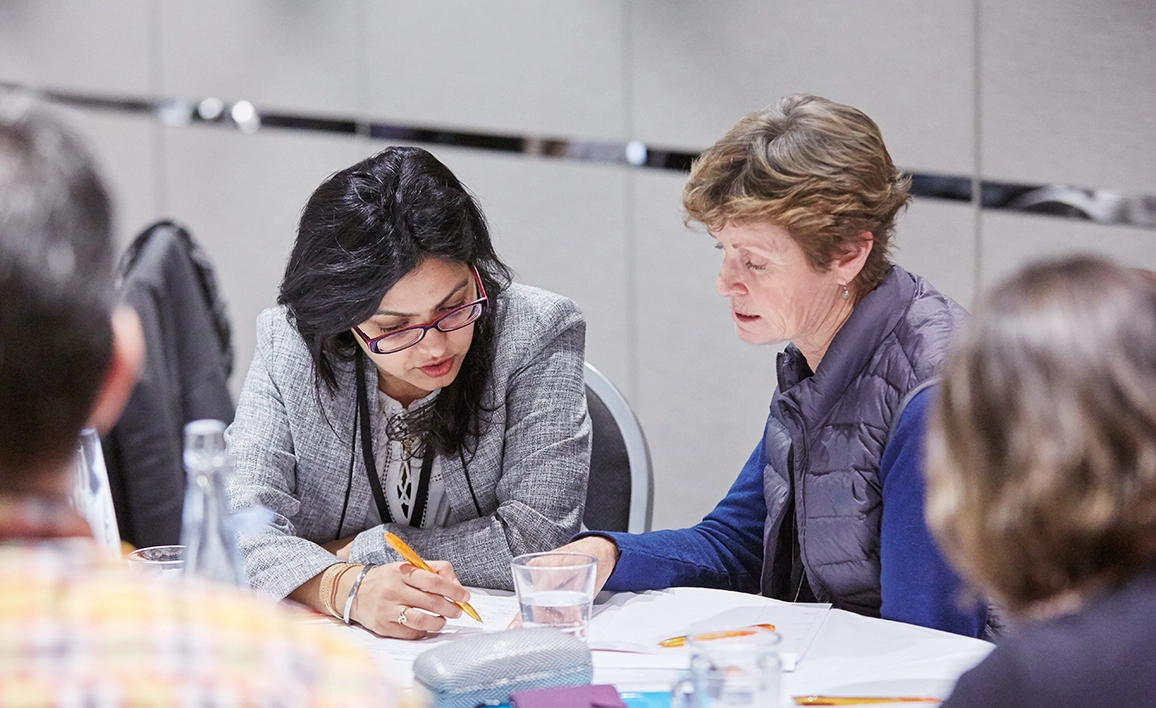 Two professionals discussing a document at a round table. 