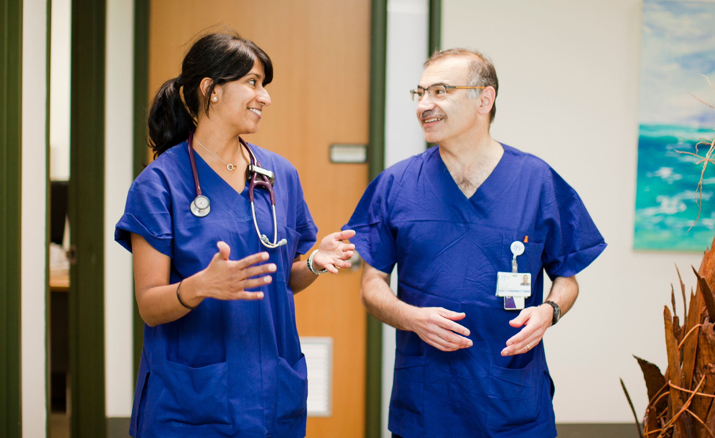 Two doctors in scrubs talking to each other